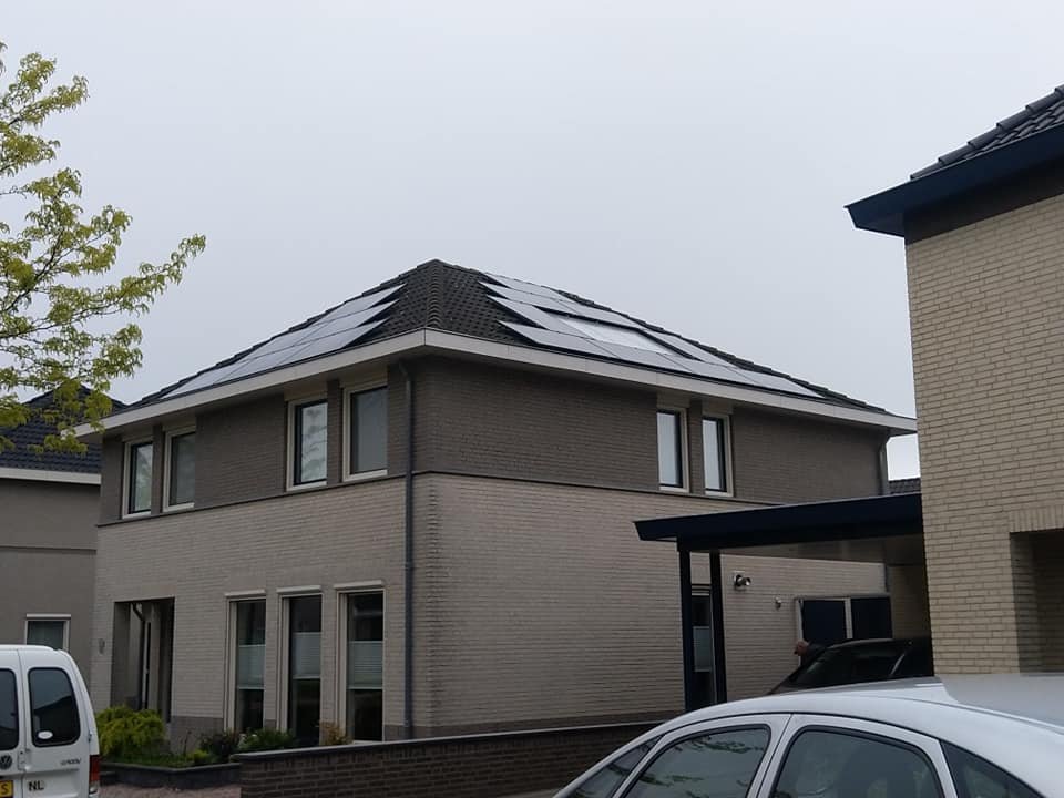 Zwarte zonnepanelen op het schilddak van een hoekwoning