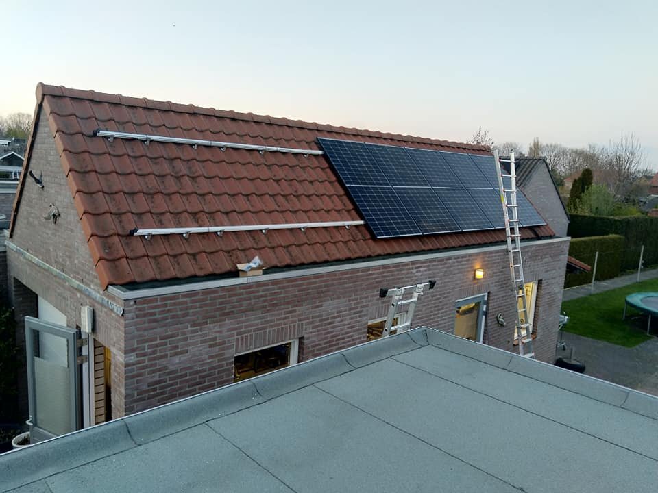 Montagerails en de eerste panelen op een schuin pannendak in avondlicht