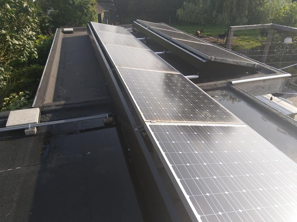 Opstelling met zonnepanelen op een plat dak in tegenlicht