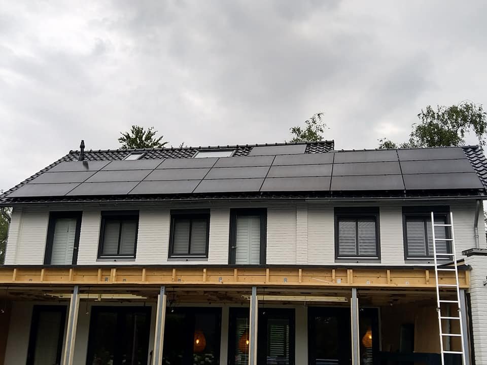 Lang dakvlak van een witte woning volledig belegd met full black panelen
